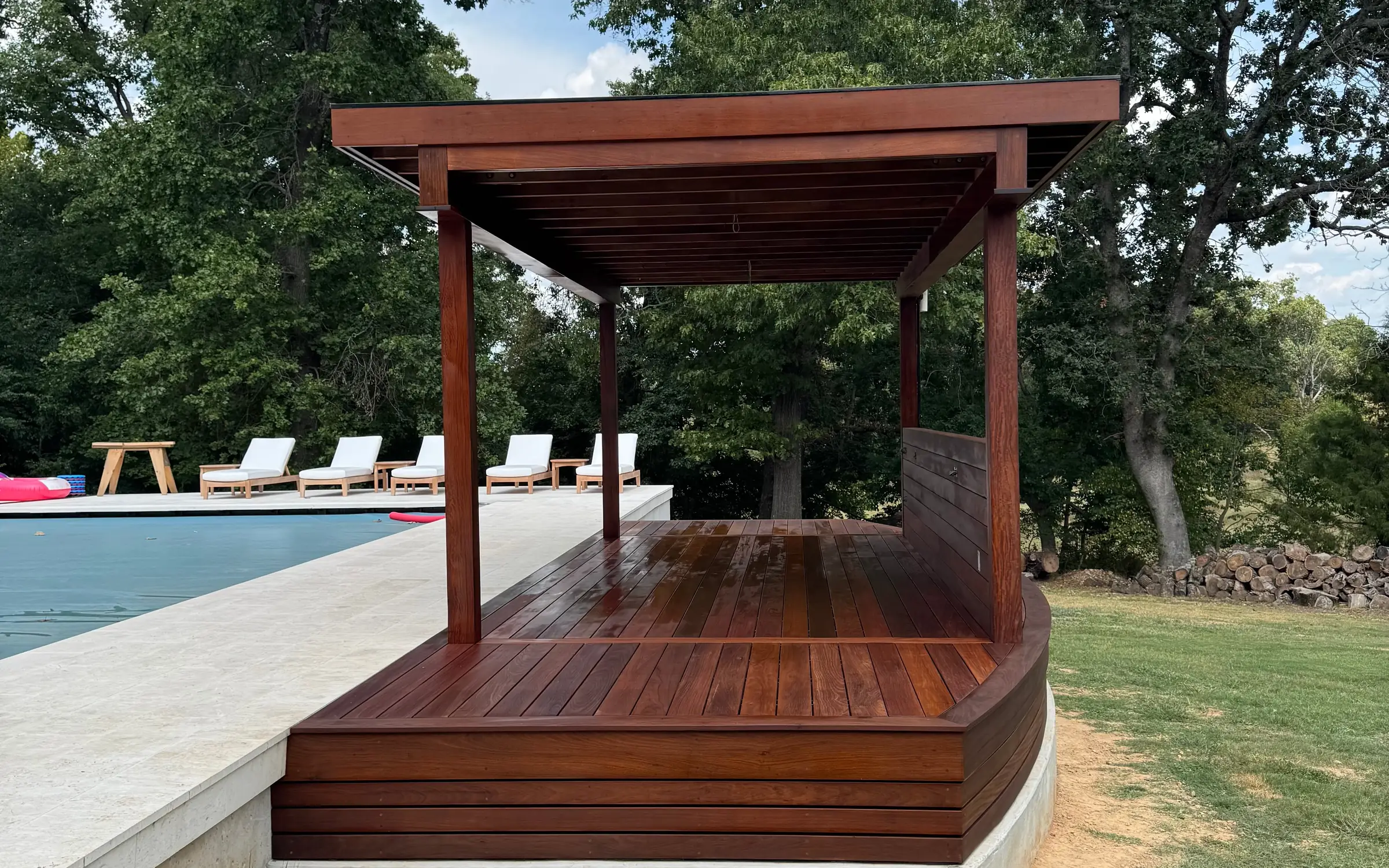 Finished ipe pergola pavilion with seating beside a pool