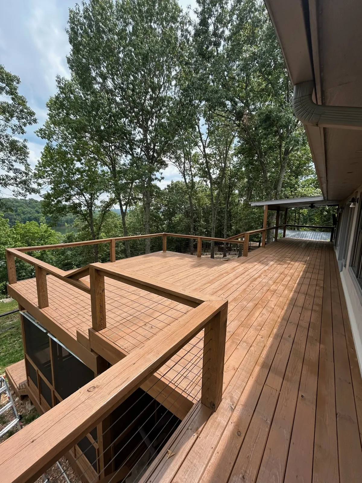 Wide ipe deck with wire rail and lake hillside view