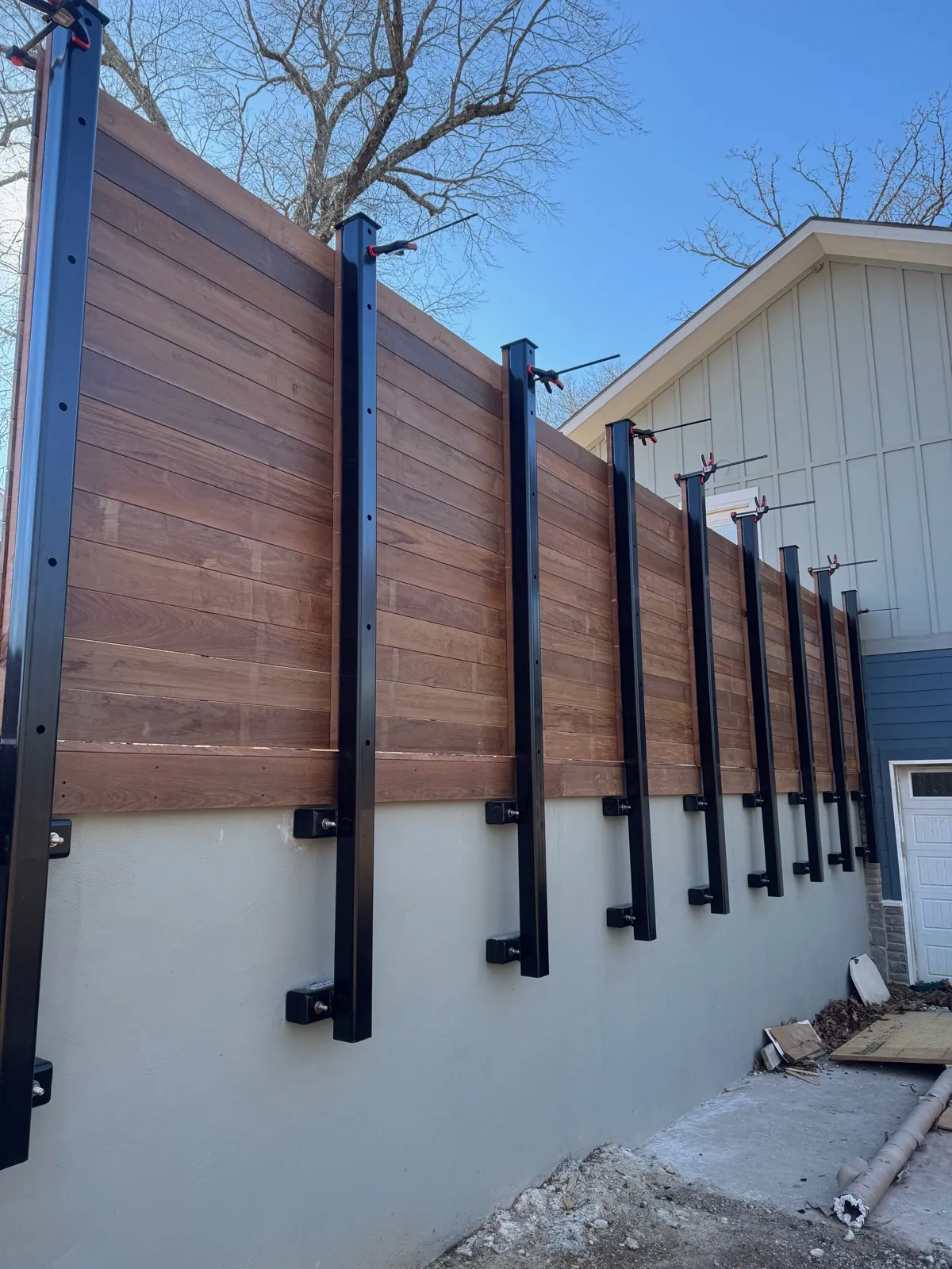 Ipe slat fence on steel posts above a concrete wall